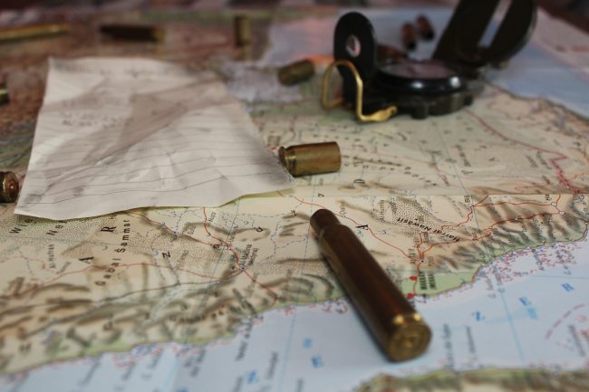 Obraz przedstawia mapę półwyspu arabskiego, na której leżą łuski i kompas.